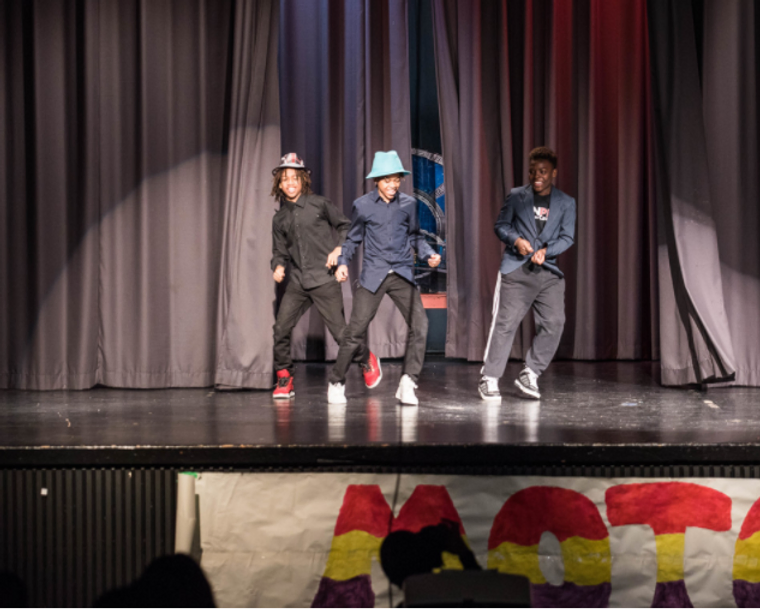 three young black tennagers on stage wearing hats and dancing